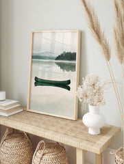 Green canoe floating on a calm, misty lake with a mountain and forest background in a, in an alternate framed mockup