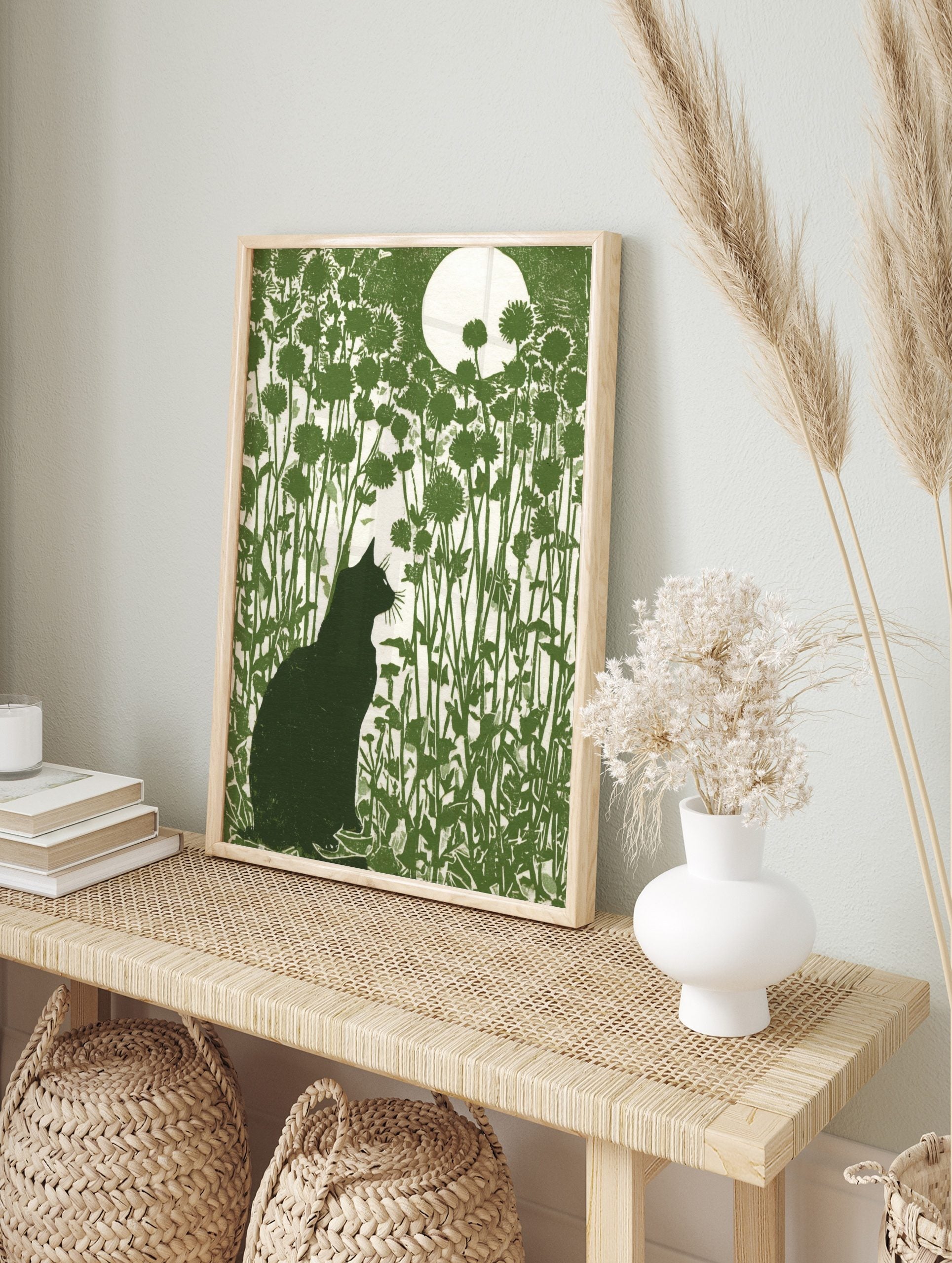 Green linocut print of a black cat silhouette in a field of flowers under a large white moon, in an alternate framed mockup