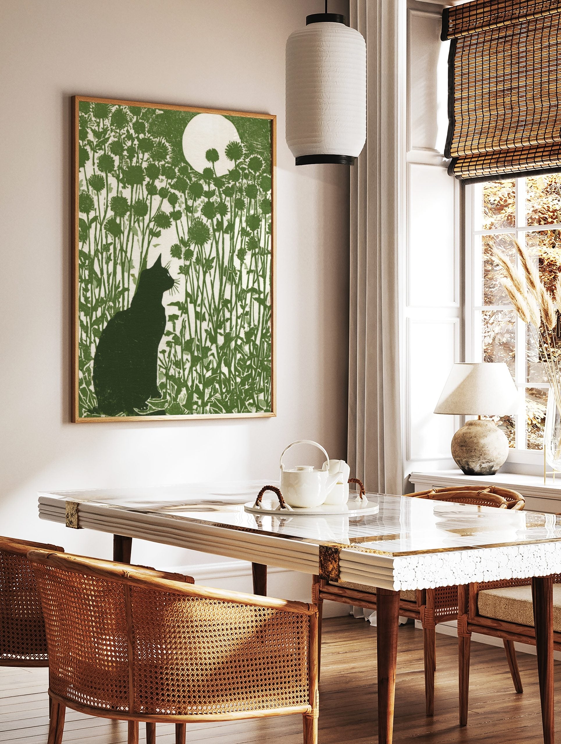 Green linocut style art print of a black cat, tall flowers, and a full moon, in a styled room mockup