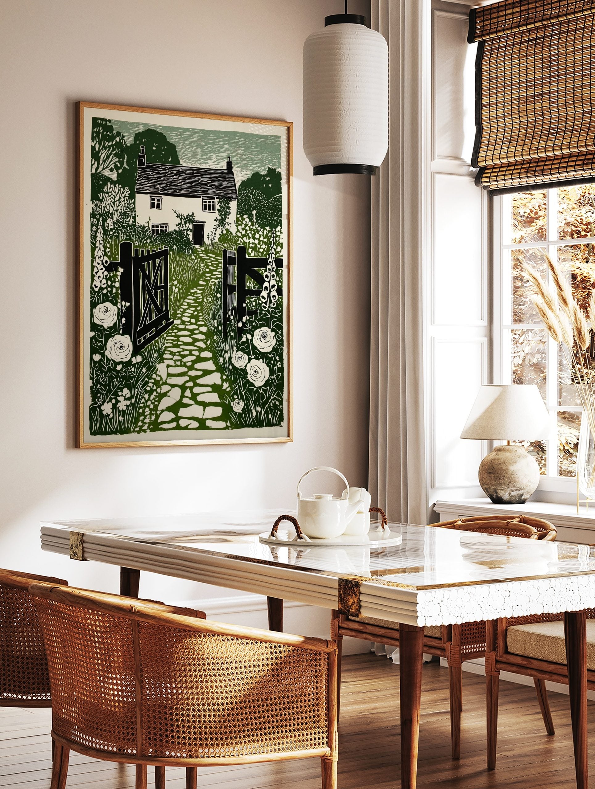 Green linocut print of a British cottage garden with open gate, cobbled path, foxgloves, and roses, in a styled room mockup