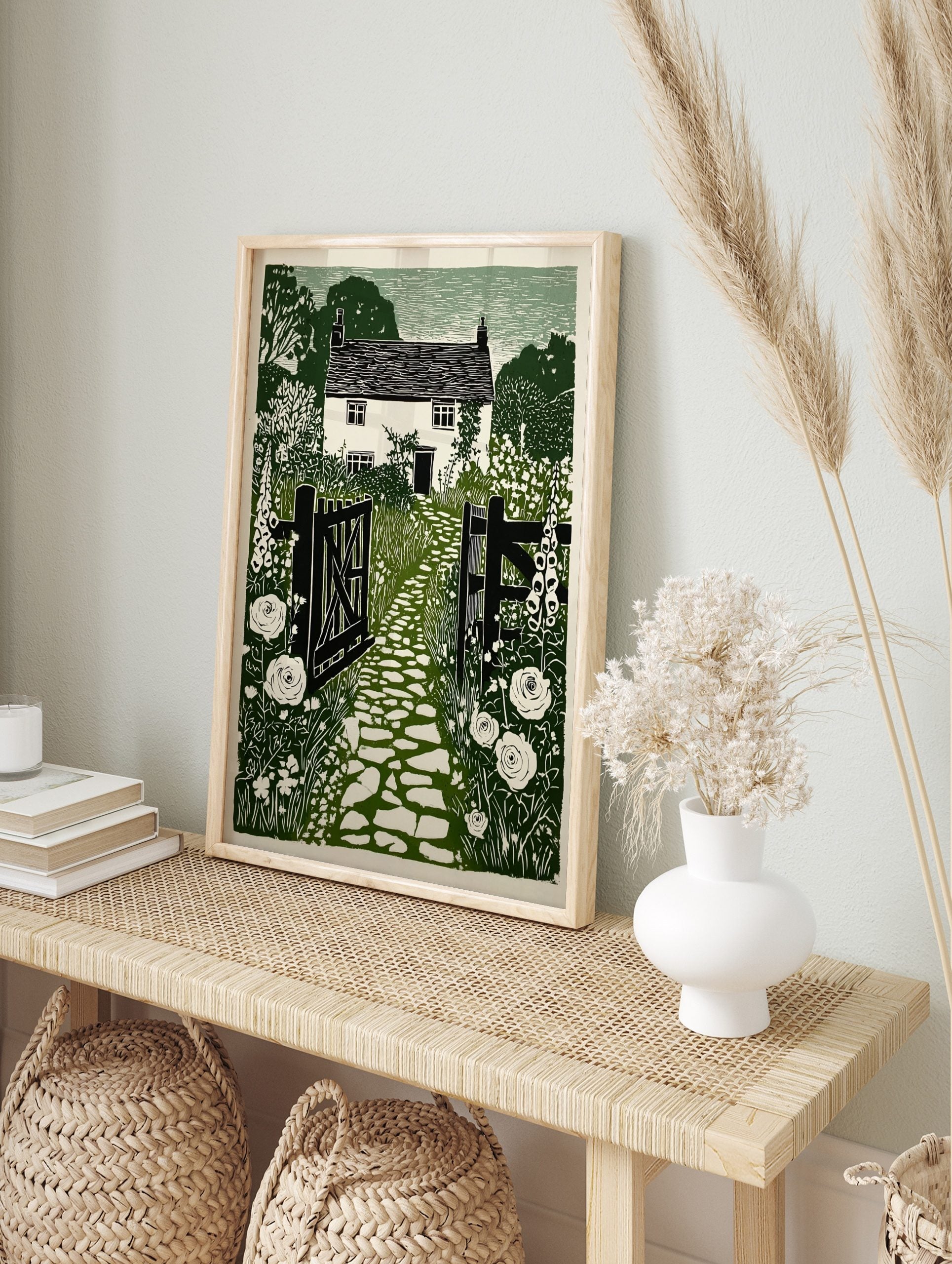 Green and white linocut style print of a cottage garden with a stone path, open gate, and, in an alternate framed mockup