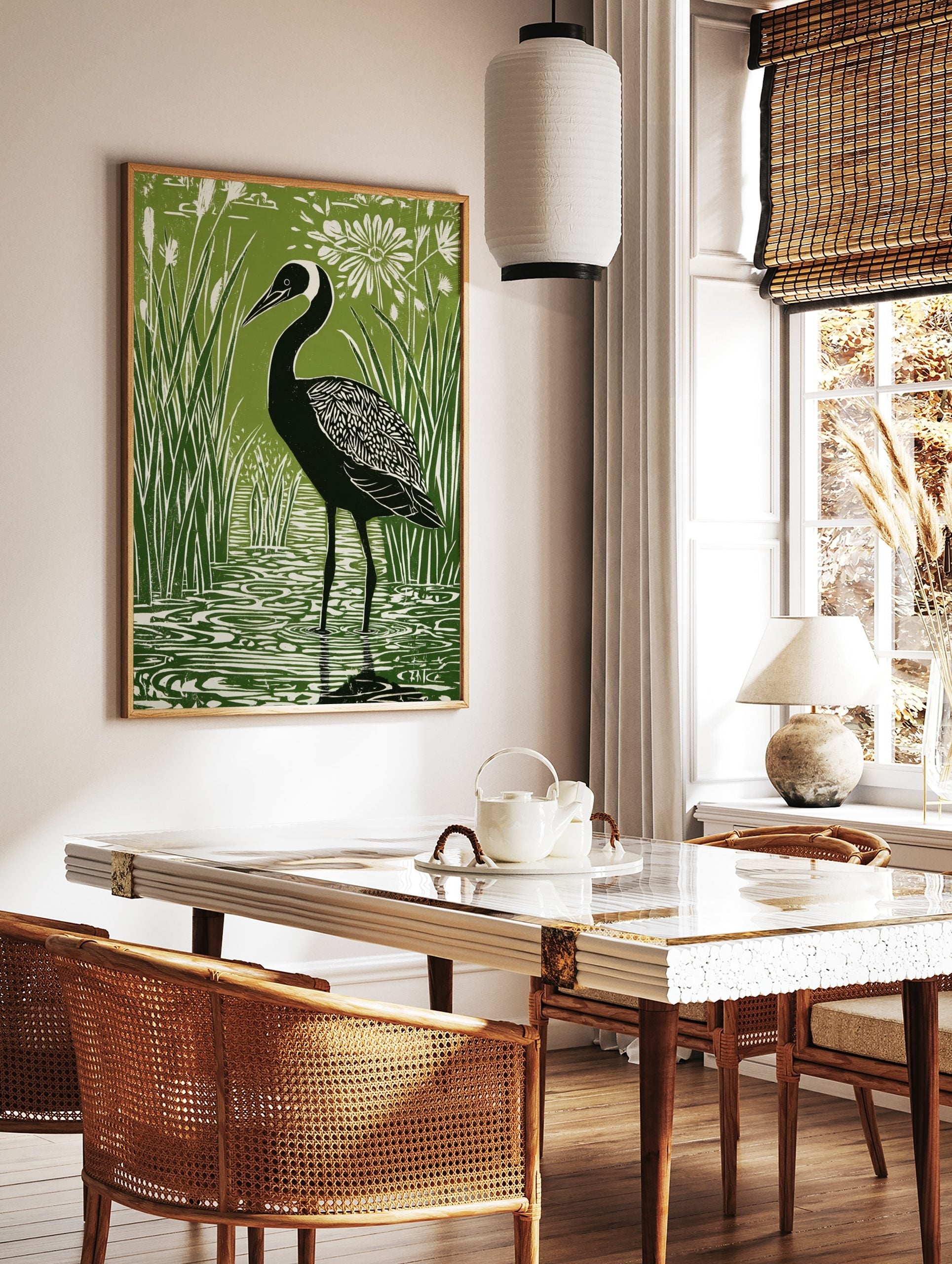 Green and white linocut style print of a black crane bird in reeds and water with a white flower, in a styled room mockup