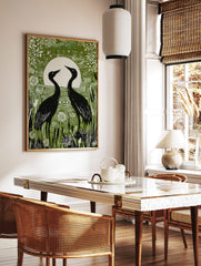 Green linocut style print of two black crane birds facing a white full moon in a wetland with white, in a styled room mockup