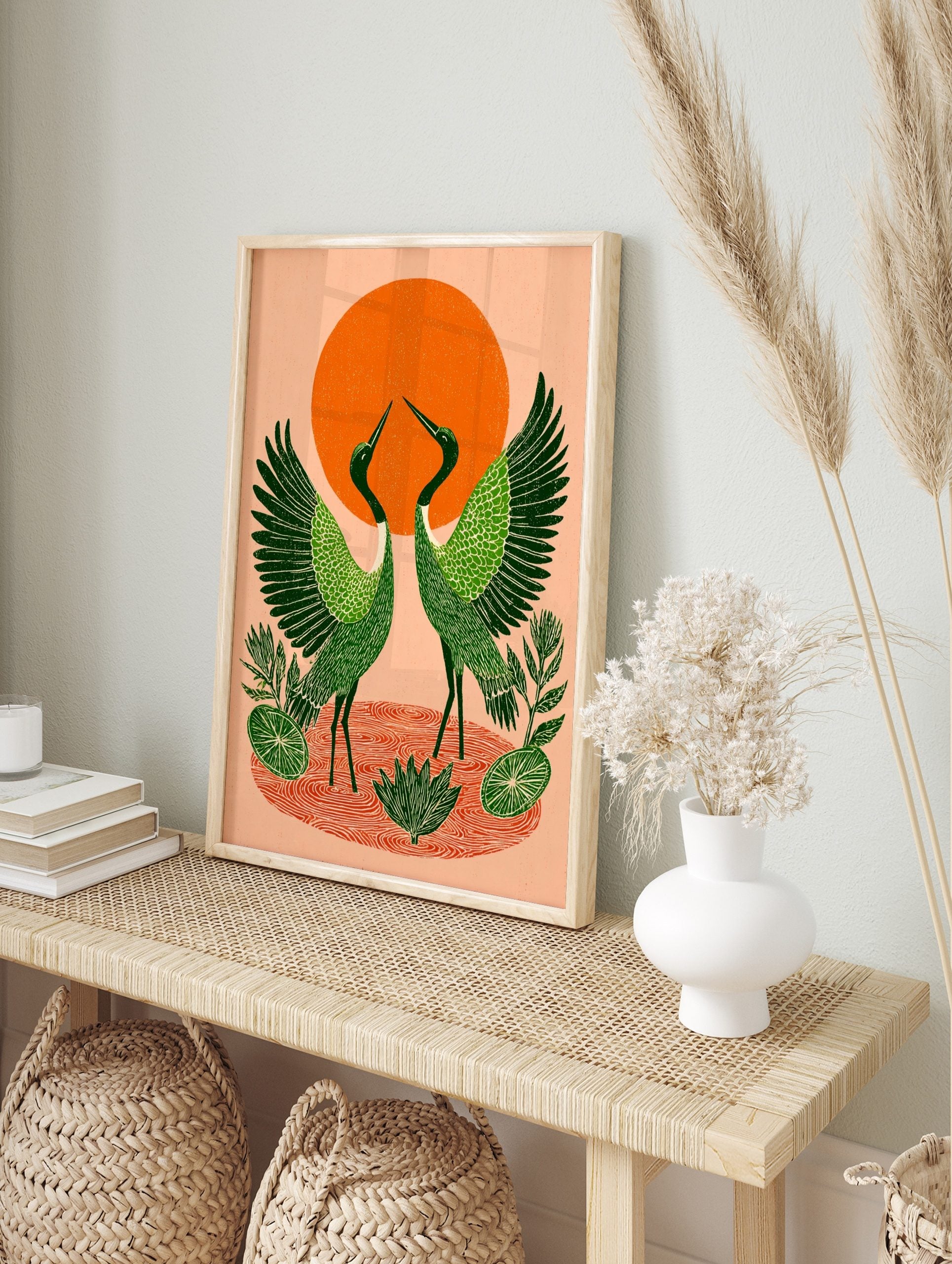 Illustrative green cranes with spread wings, orange sun, and water ripples print, in an alternate framed mockup