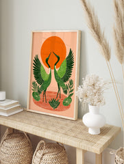 Illustrative green cranes with spread wings, orange sun, and water ripples print, in an alternate framed mockup