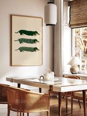 Three illustrative green dachshund dogs, one plain, one floral, one striped, on a light background, in a styled room mockup