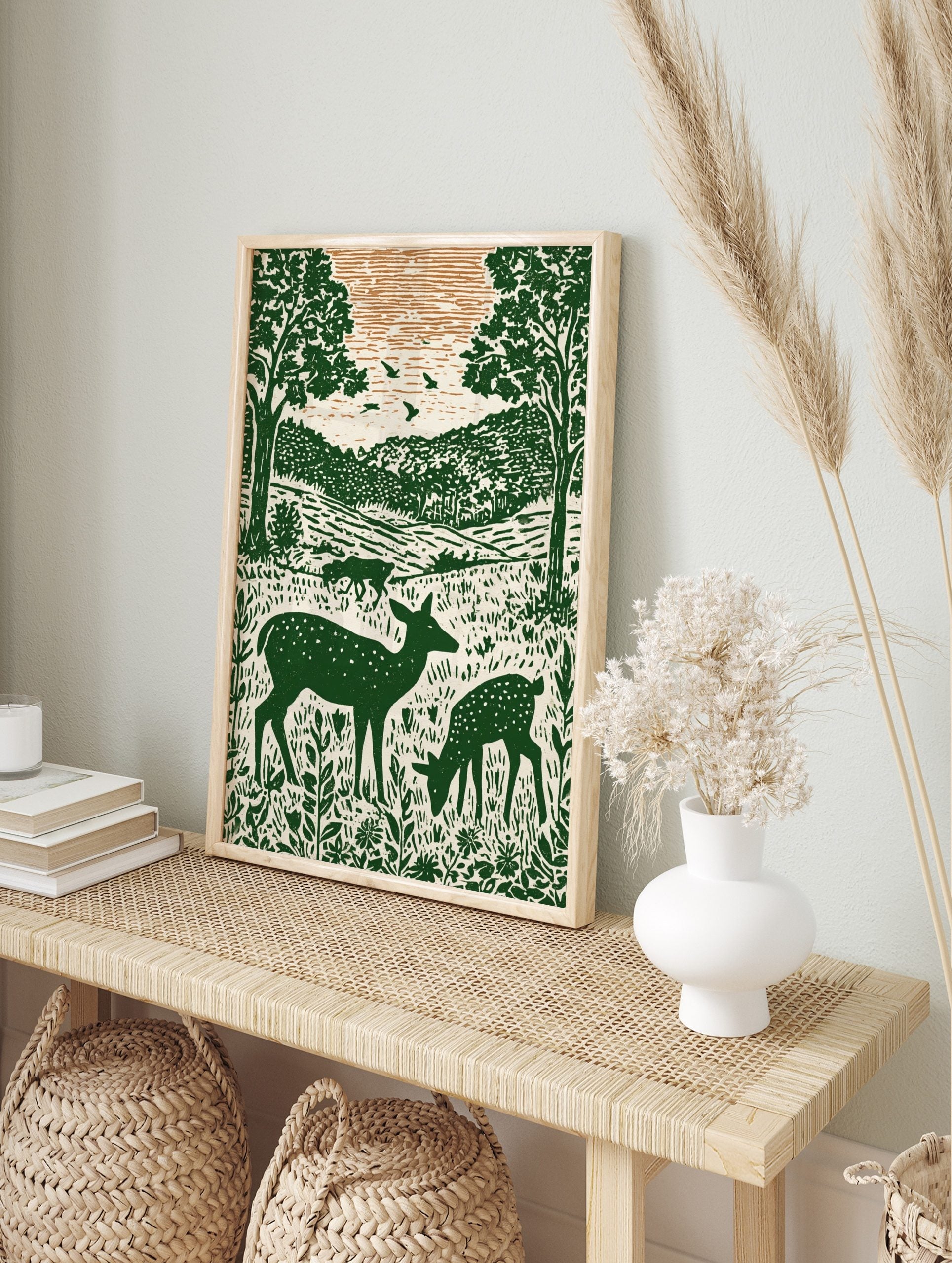 Illustrative green deer family in forest with trees and hills, woodcut style nature print, in an alternate framed mockup