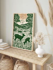 Illustrative green deer family in forest with trees and hills, woodcut style nature print, in an alternate framed mockup