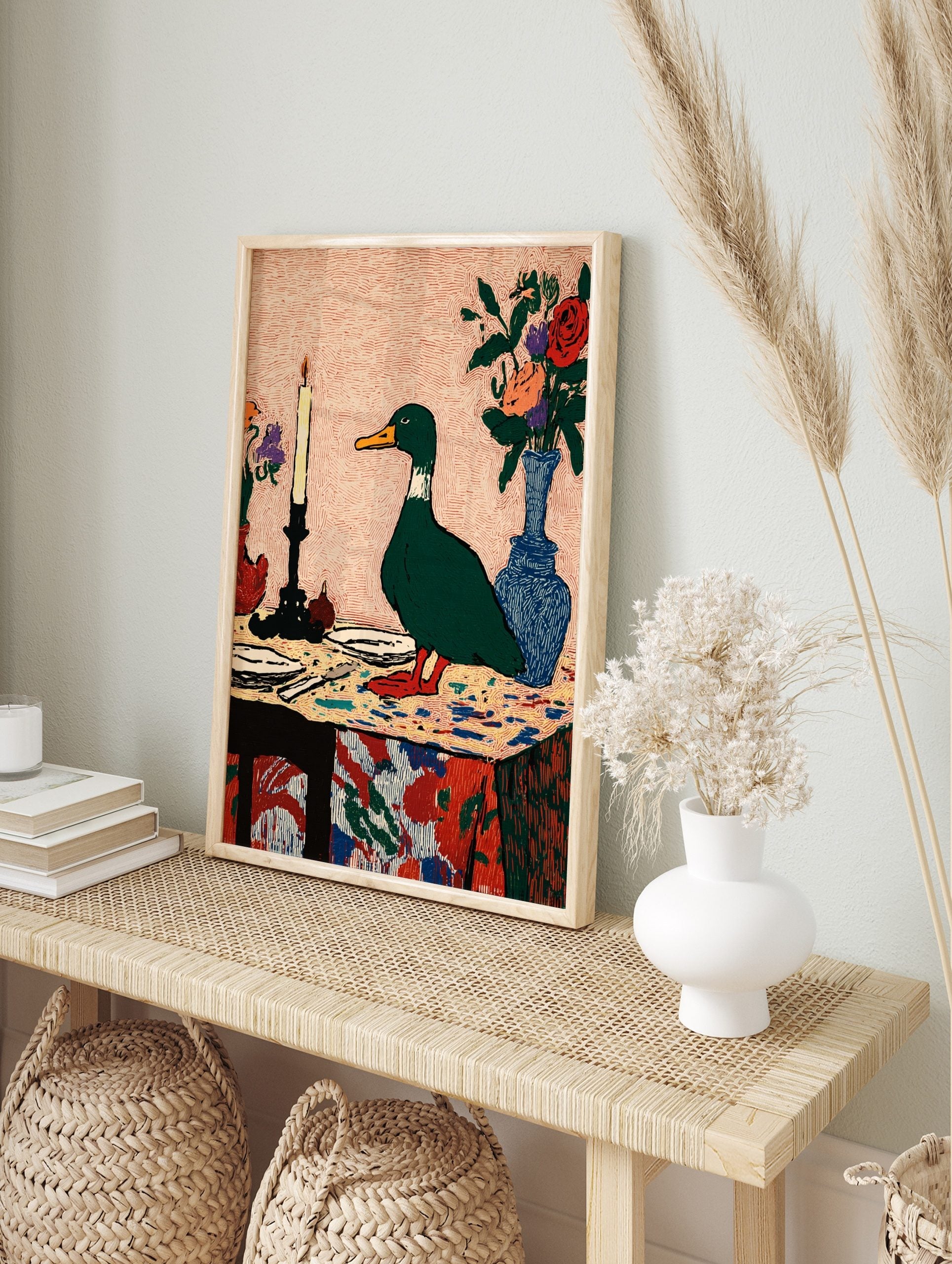 Illustrative green duck standing on a colourful table with a lit candle and flower vases, in an alternate framed mockup