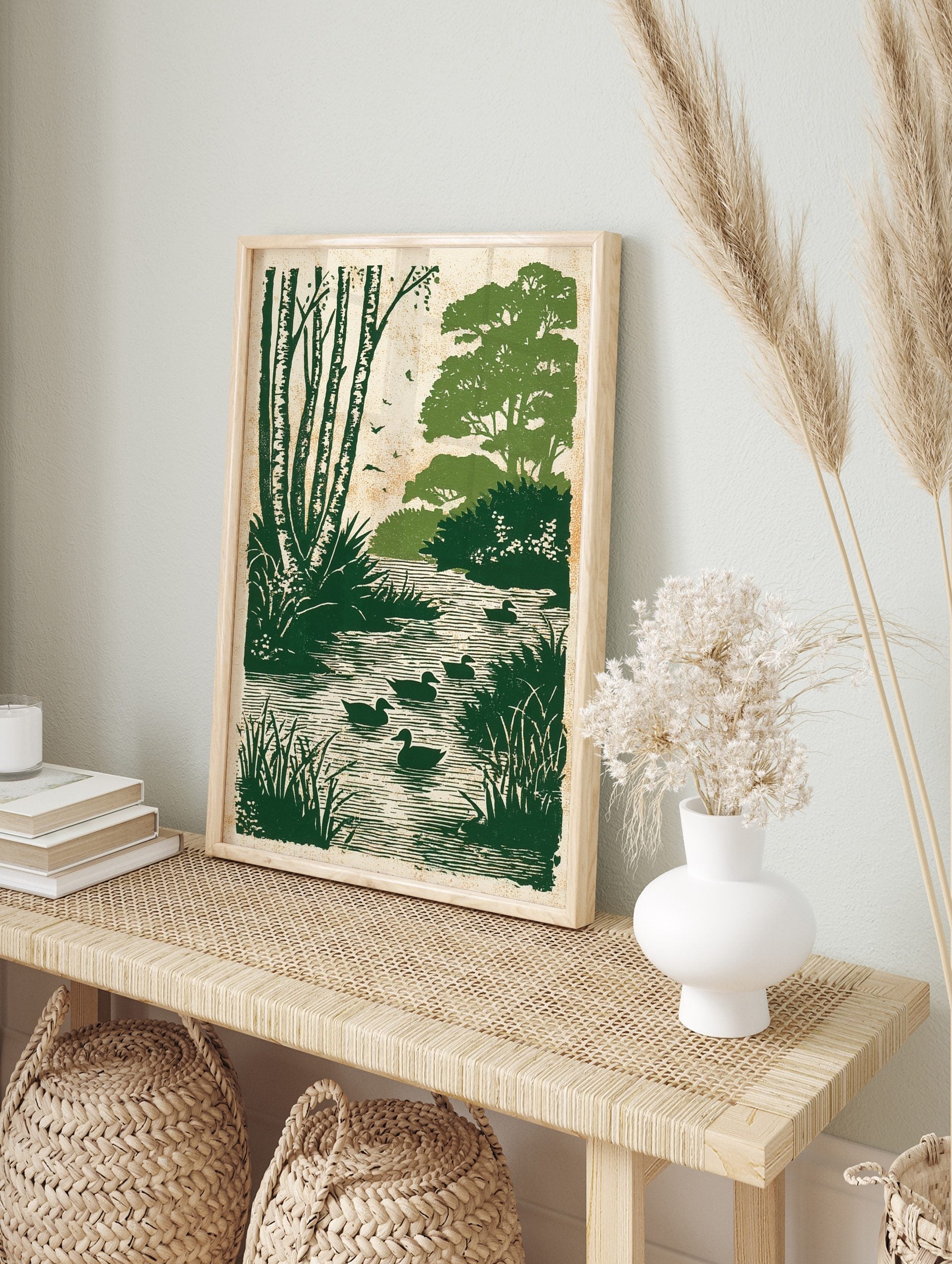 Green ducks swimming in a river with birch trees and foliage in an illustrative print style, in an alternate framed mockup