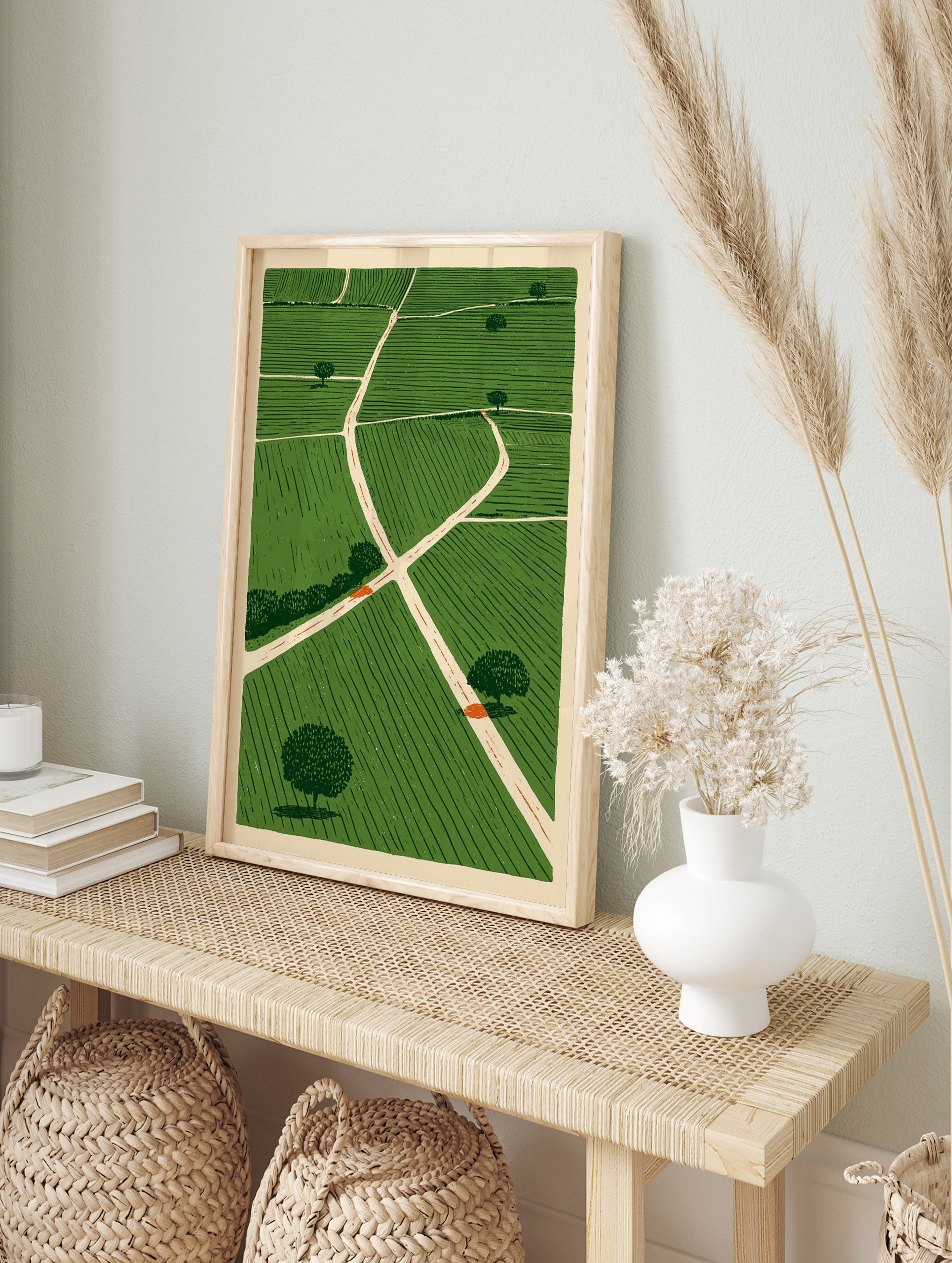 Illustrative green fields landscape wall art with intersecting paths and scattered trees on a, in an alternate framed mockup