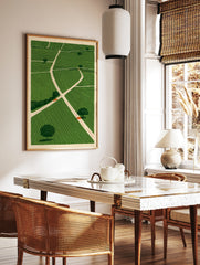 Illustrative green fields landscape wall art with intersecting paths and scattered trees on a, in a styled room mockup