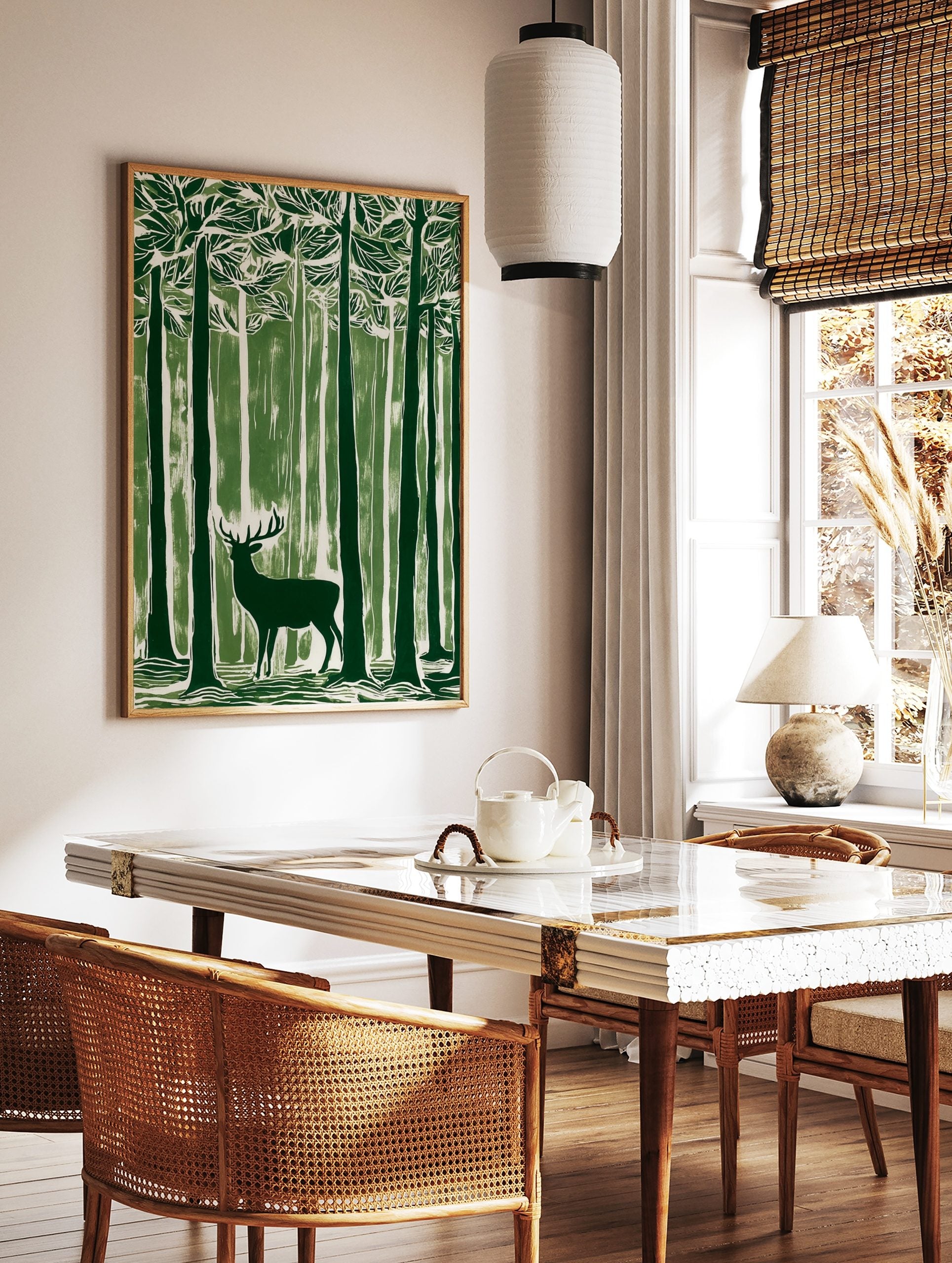 Green linocut style art print of a stag with antlers standing in a dense forest of tall trees, in a styled room mockup