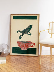 Green frog leaping over a red patterned teacup on a beige background with green stripes. Frog art print. - Image 2