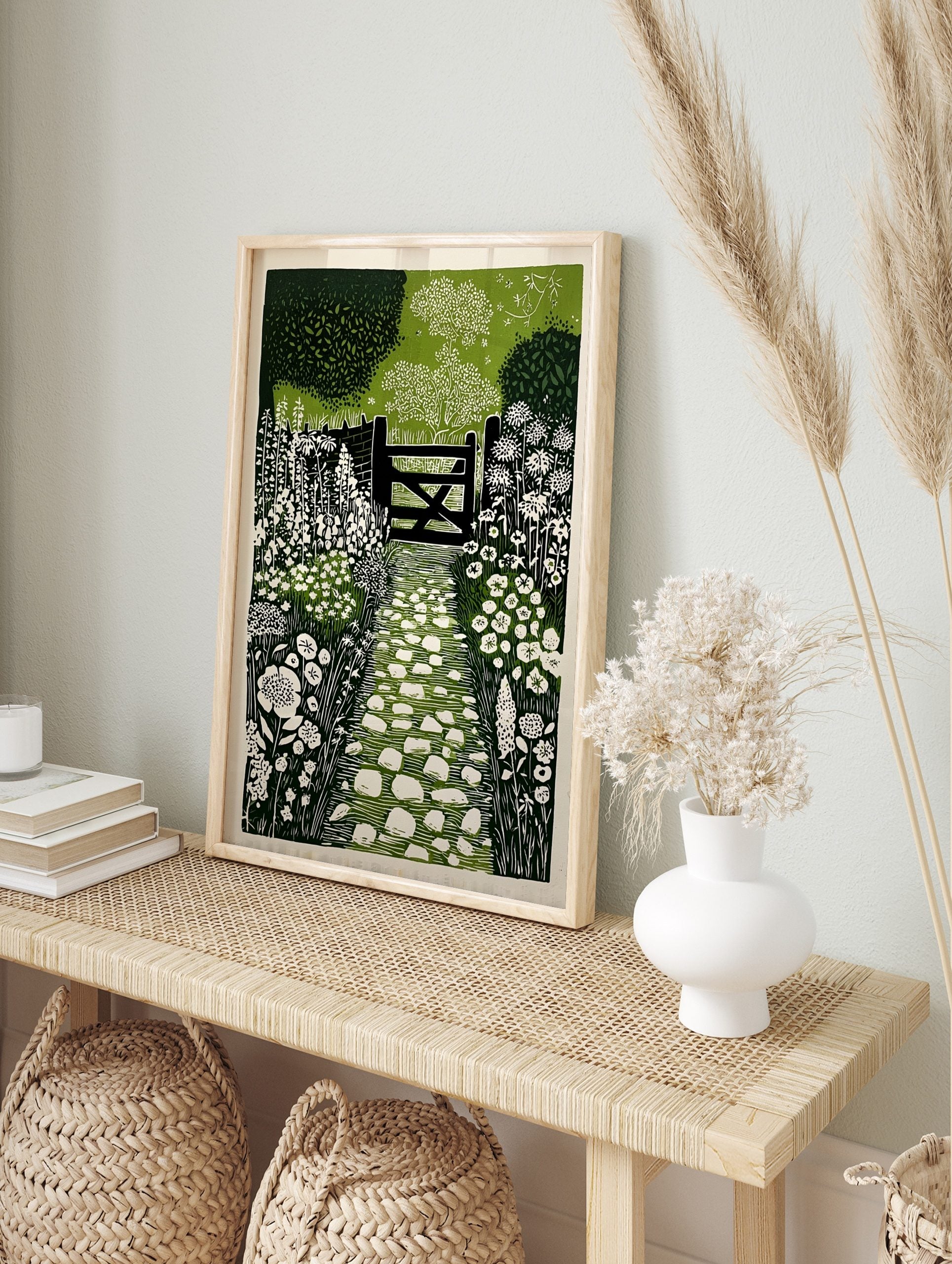 Linocut print of a garden path with white stepping stones leading to a dark wooden gate and, in an alternate framed mockup