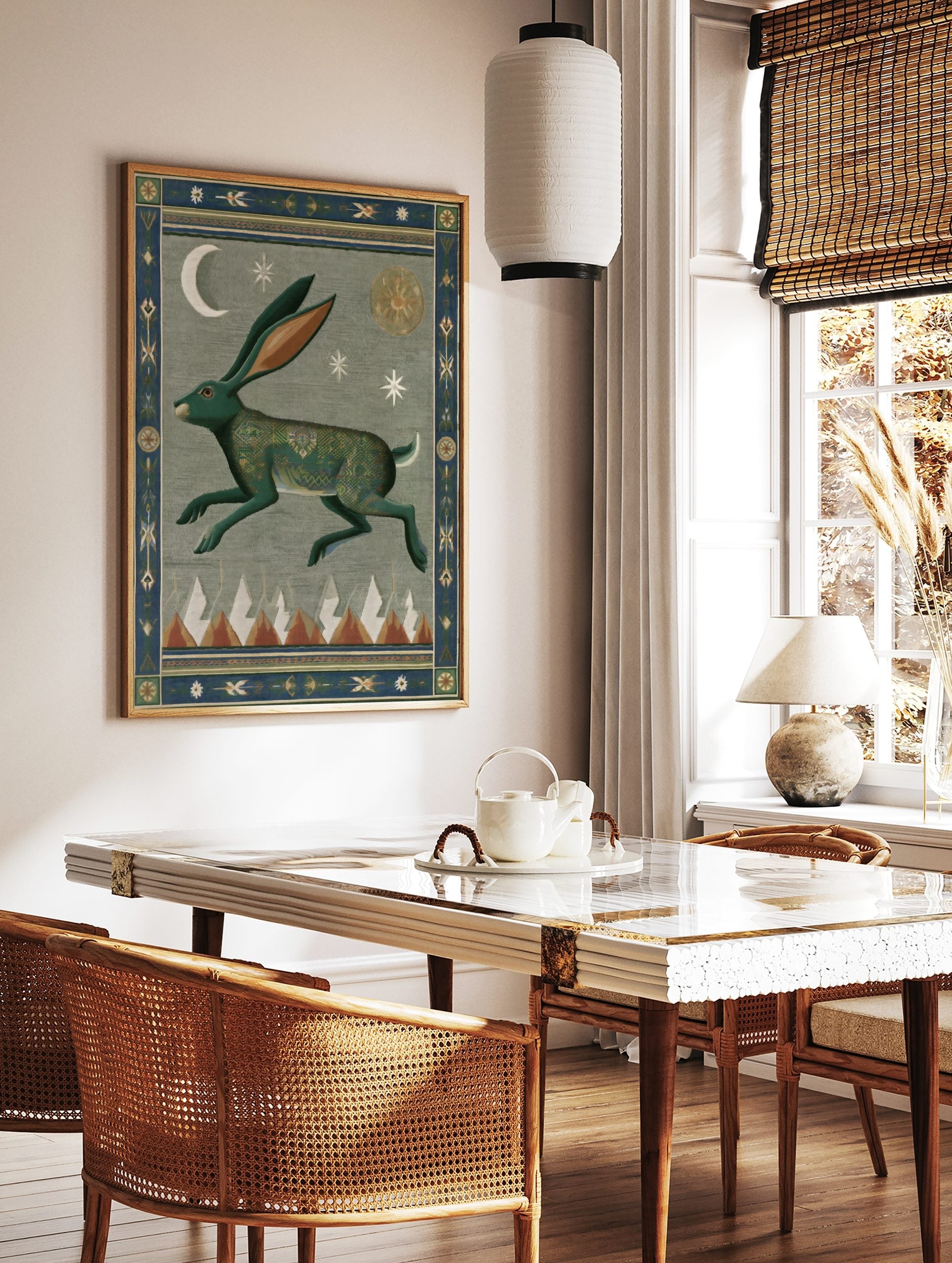 Stylized green hare wall art print with intricate patterns, crescent moon, sun, stars, and mountain peaks, bordered by decorative motifs, displayed as the same artwork in a styled poster mockup for home decor