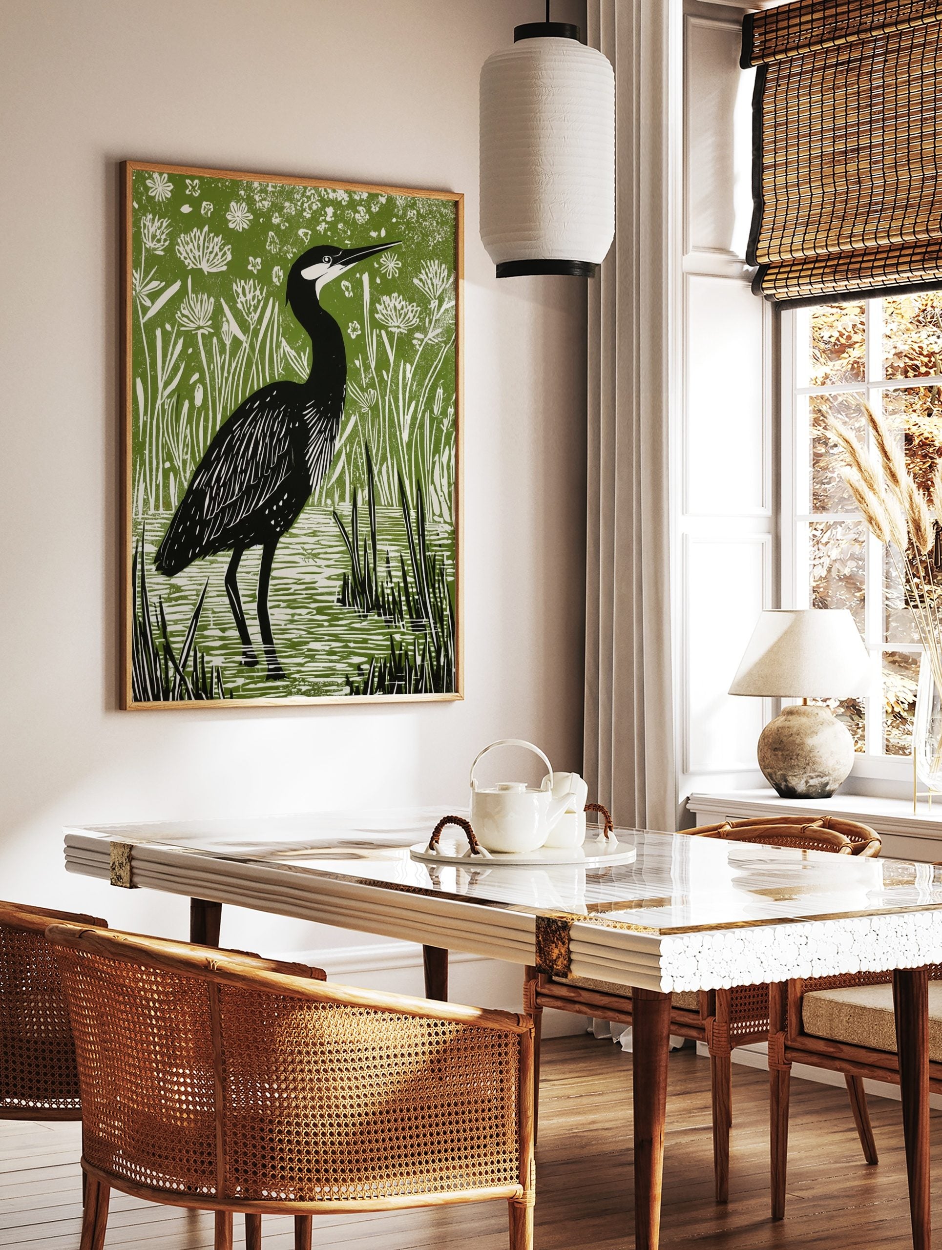 Illustrative linocut print of a black heron with white head markings, standing in green marsh water, in a styled room mockup