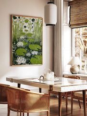 Green lily pads, white water lilies, and tall reeds in a pond, linocut-style botanical print, in a styled room mockup