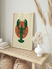 Dark green lobster illustration with textured claws and tail on a red radial sunburst, in an alternate framed mockup