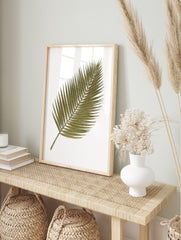Green palm leaf botanical illustration art print with white outlines on a white background, in an alternate framed mockup