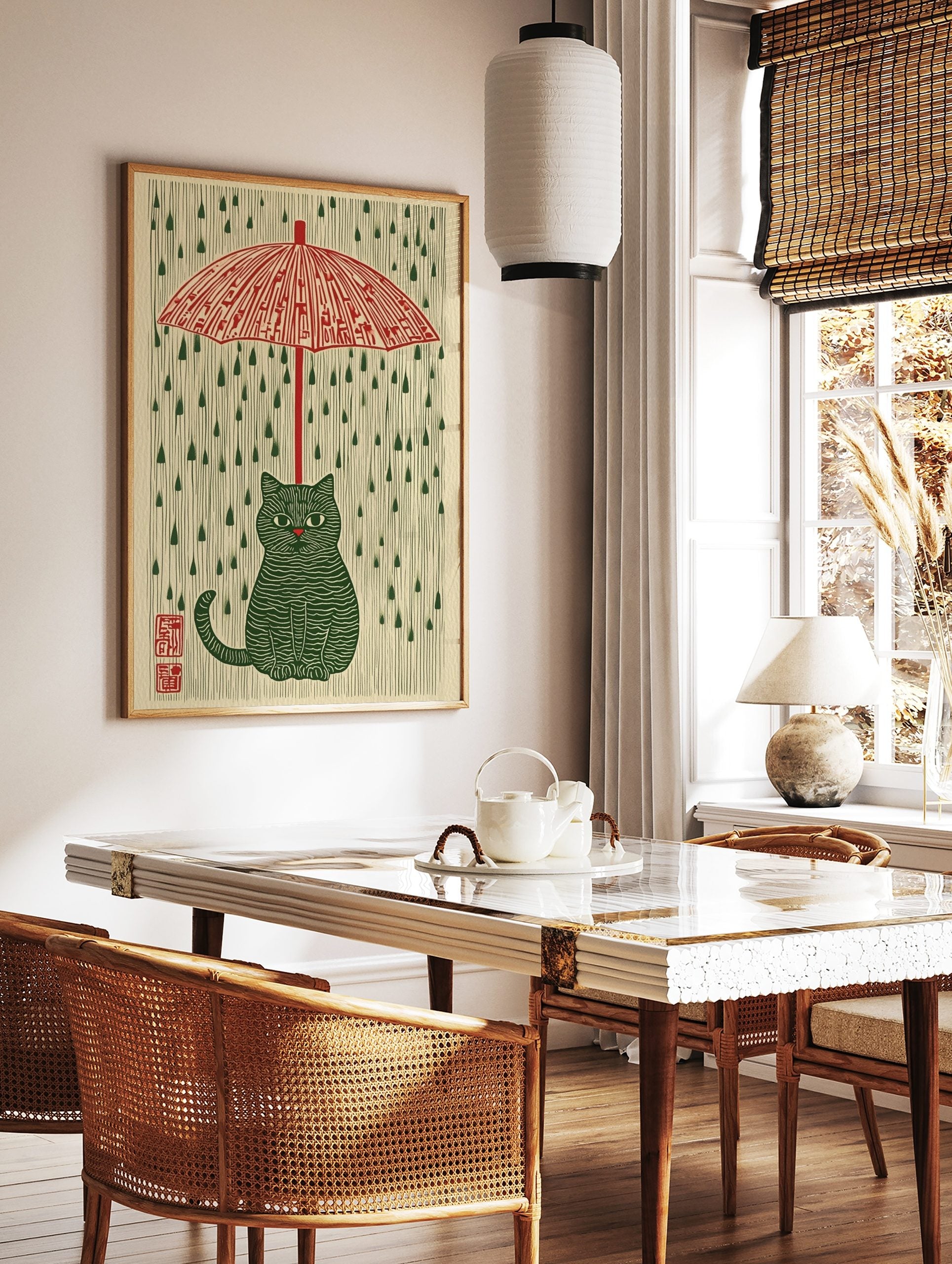 Illustrative green striped cat under a red umbrella with green raindrops on a cream background, in a styled room mockup
