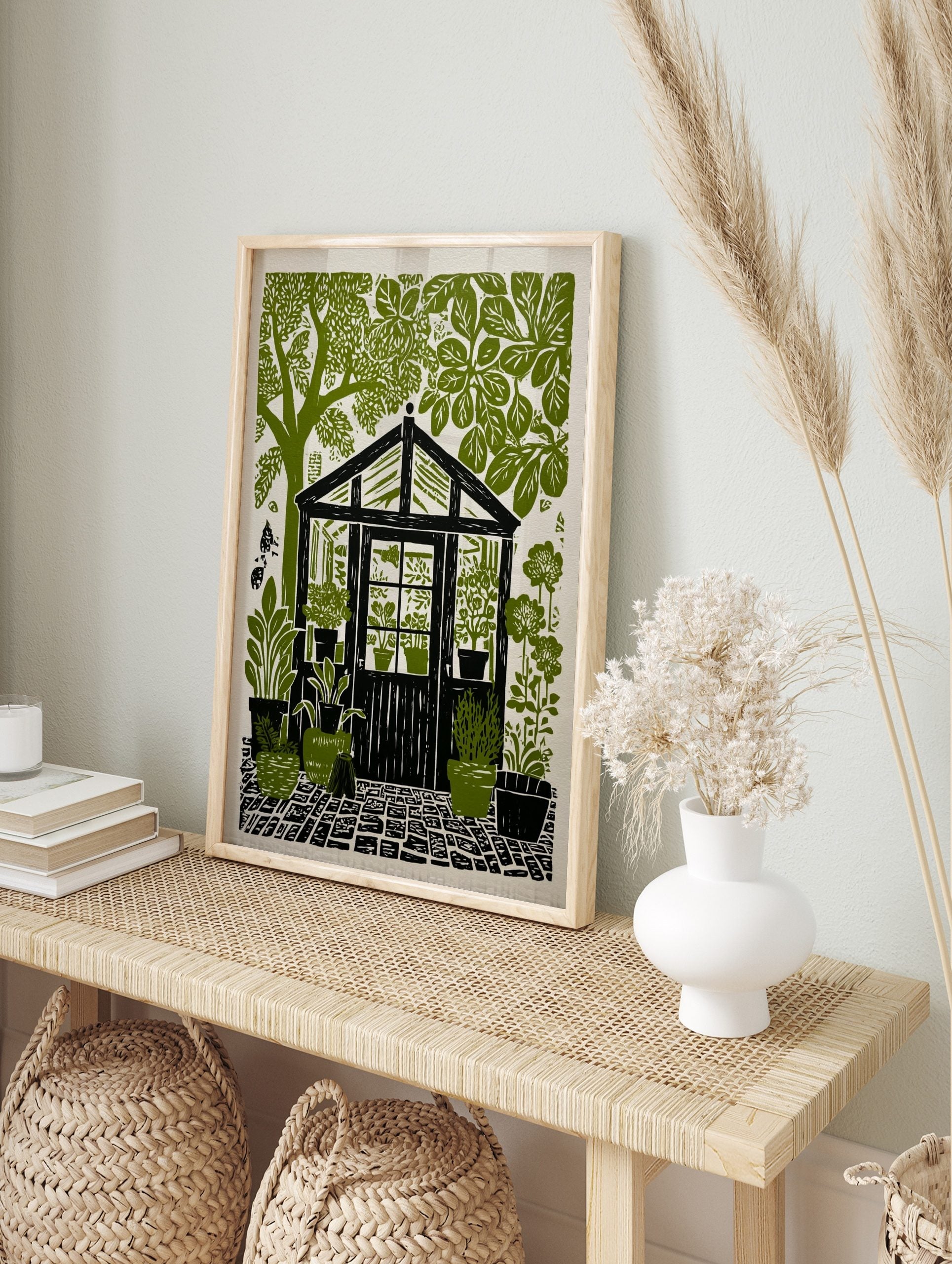 Greenhouse garden linocut print with potted plants, lush trees, and cobblestone path in green, in an alternate framed mockup