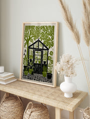 Greenhouse garden linocut print with potted plants, lush trees, and cobblestone path in green, in an alternate framed mockup