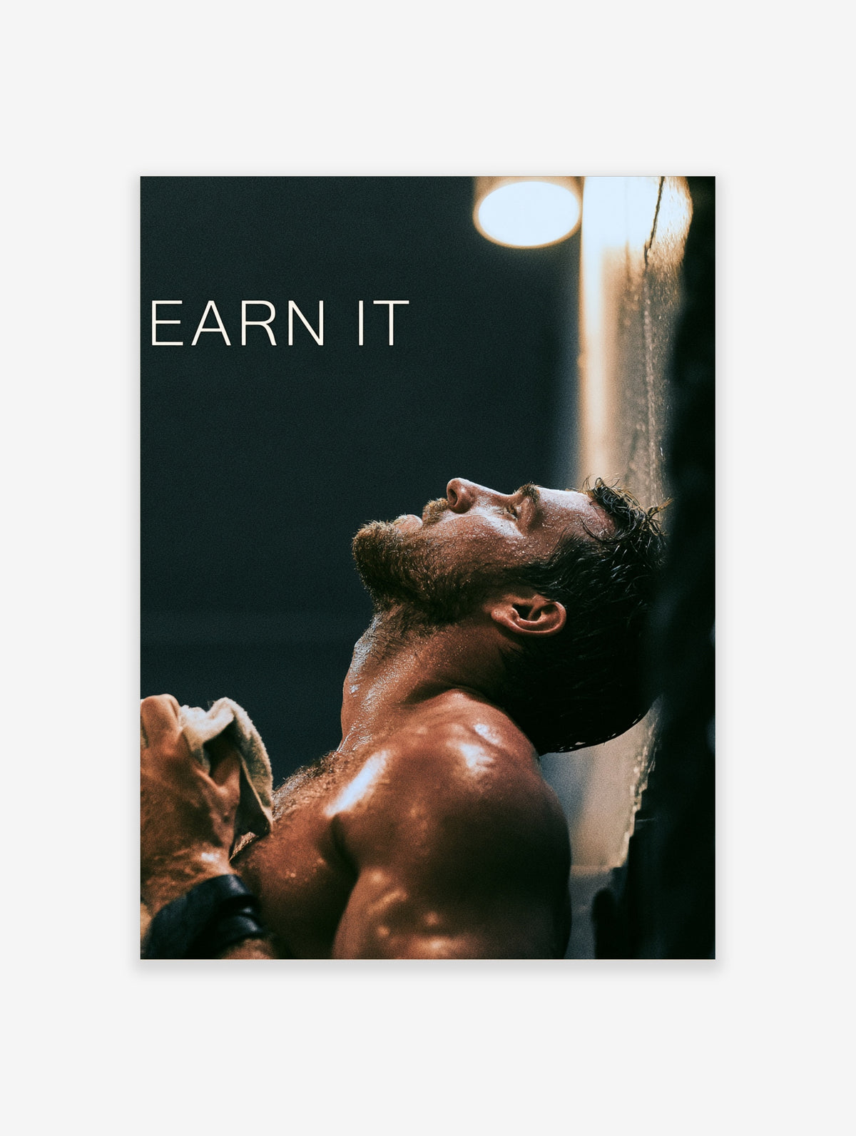 Dark gym motivation poster of a sweaty muscular man with head tilted back holding a towel, with EARN IT text
