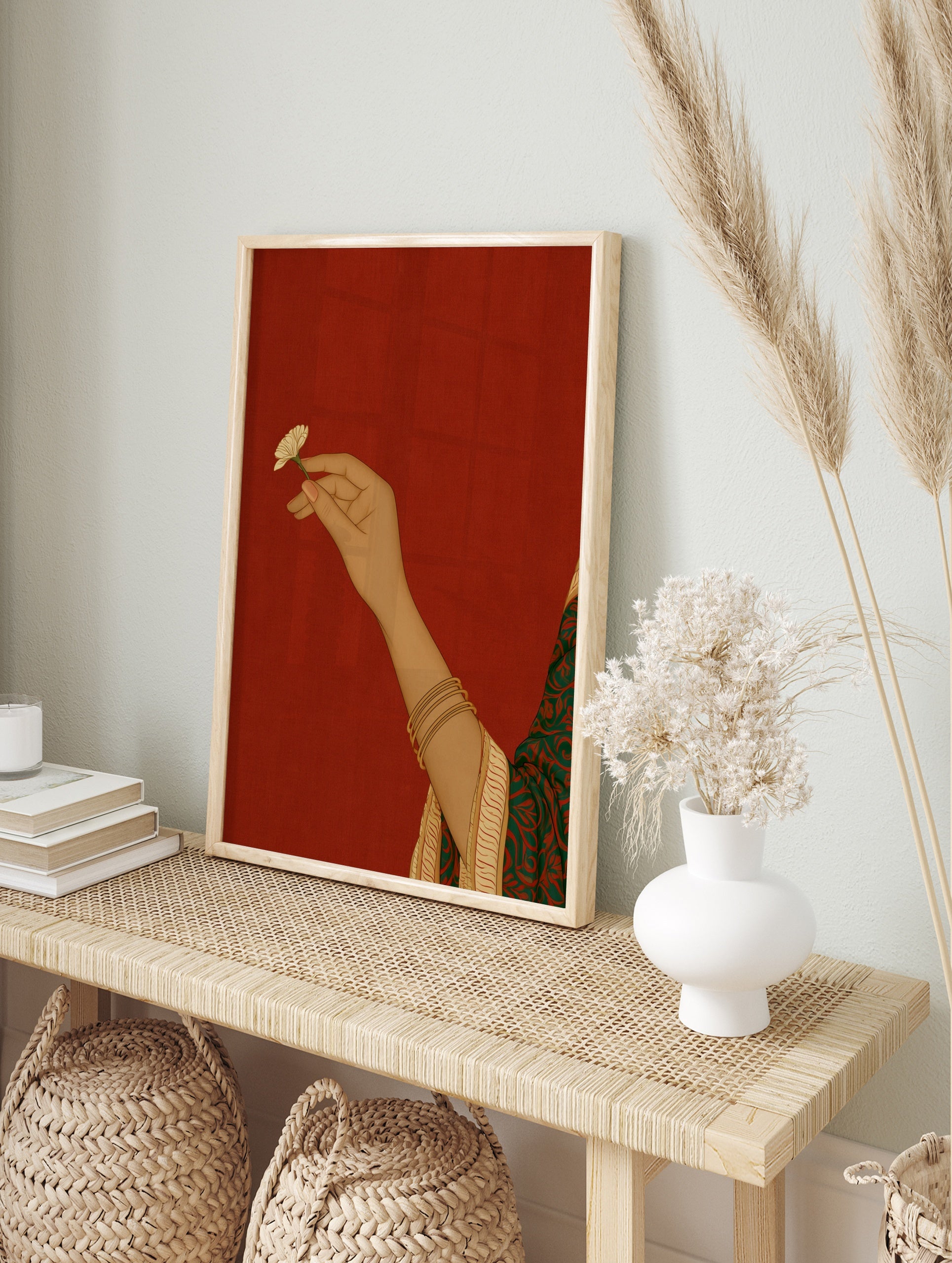 Illustrative art print of a hand holding a small flower, wearing gold bangles, set against a, in an alternate framed mockup