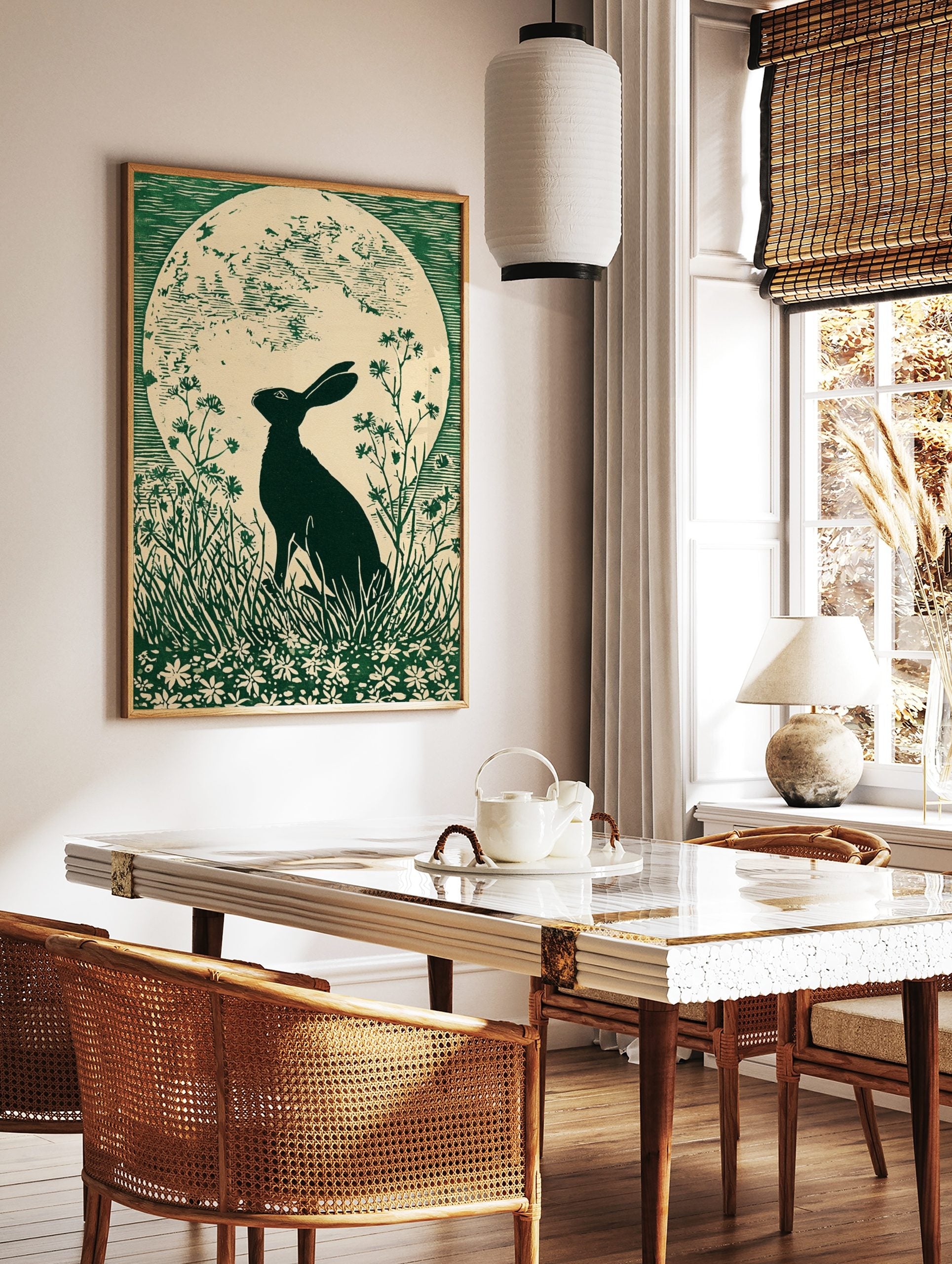 Green linocut print of a hare in silhouette looking at a large full moon, surrounded by grass and, in a styled room mockup