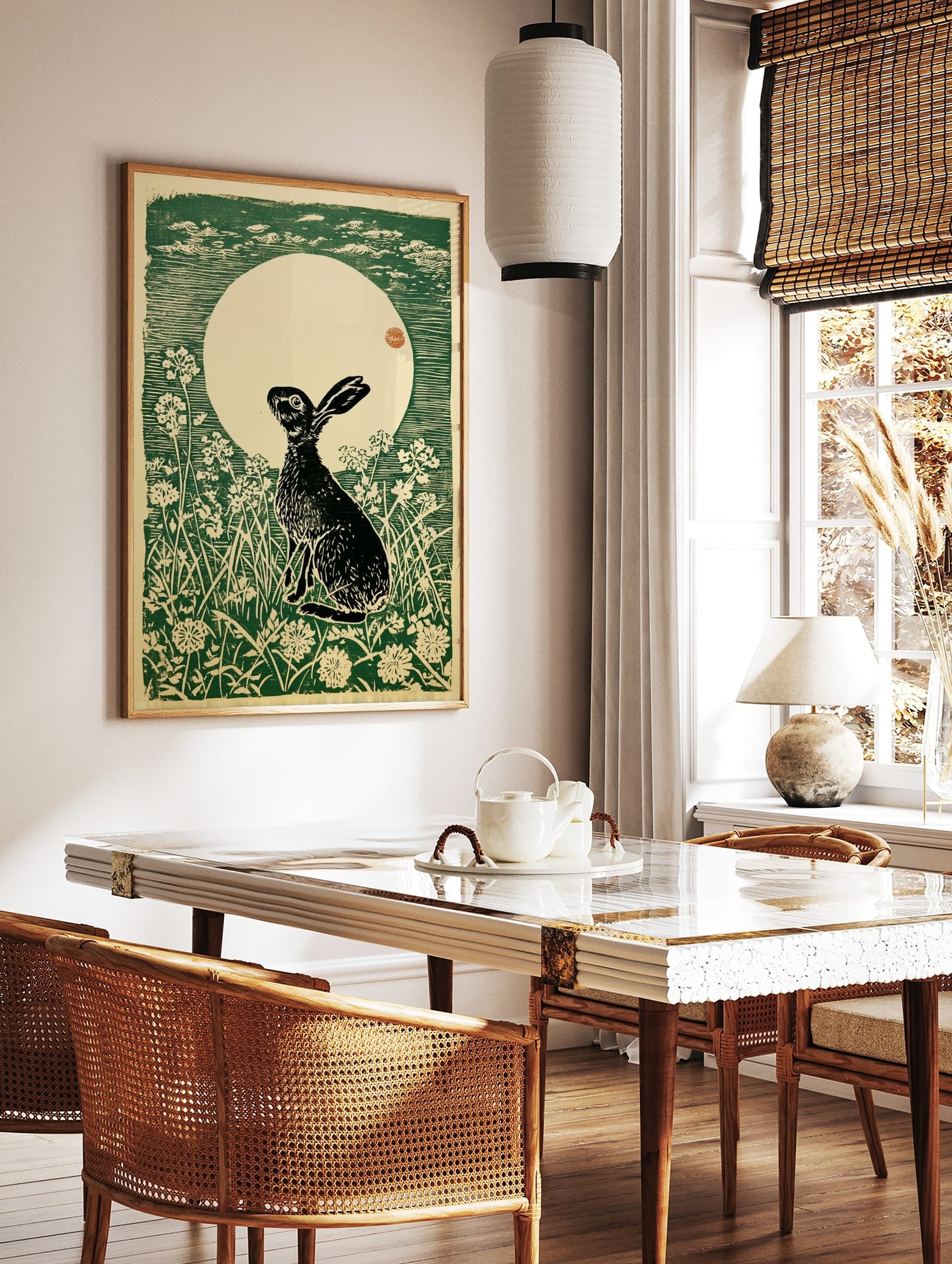 Woodcut print of a black hare looking up at a large cream moon with green sky and white flowers, in a styled room mockup