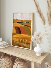 Illustrative landscape wall art of golden hay bales in a field with a distant farmstead and, in an alternate framed mockup