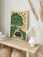 Illustrative print of a black hedgehog walking on an autumn path with green trees and falling, in an alternate framed mockup