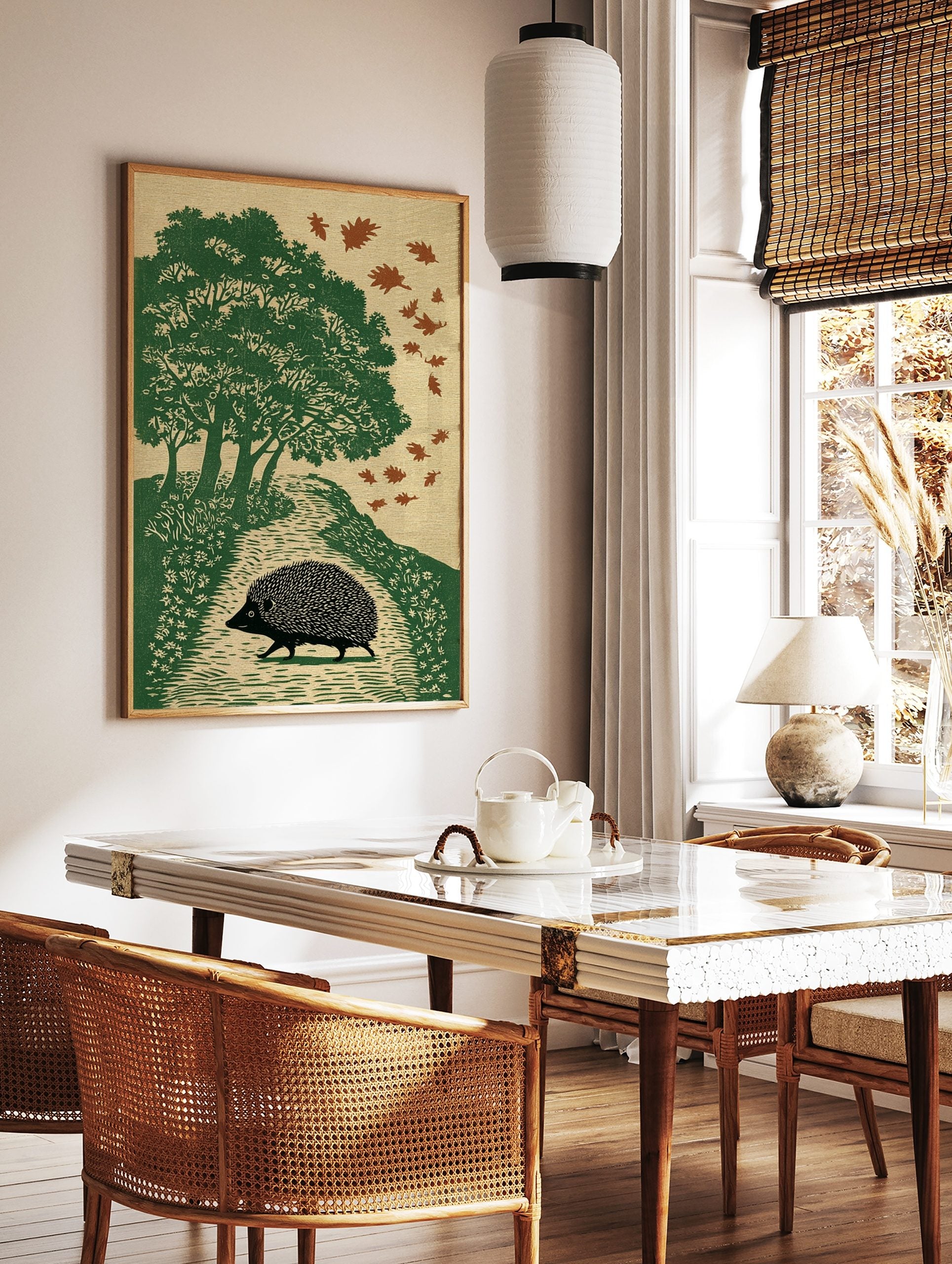 Illustrative print of a black hedgehog walking on an autumn path with green trees and falling brown, in a styled room mockup