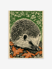 Linocut print of a hedgehog with black quills, off-white face, orange autumn leaves, and green foliage background