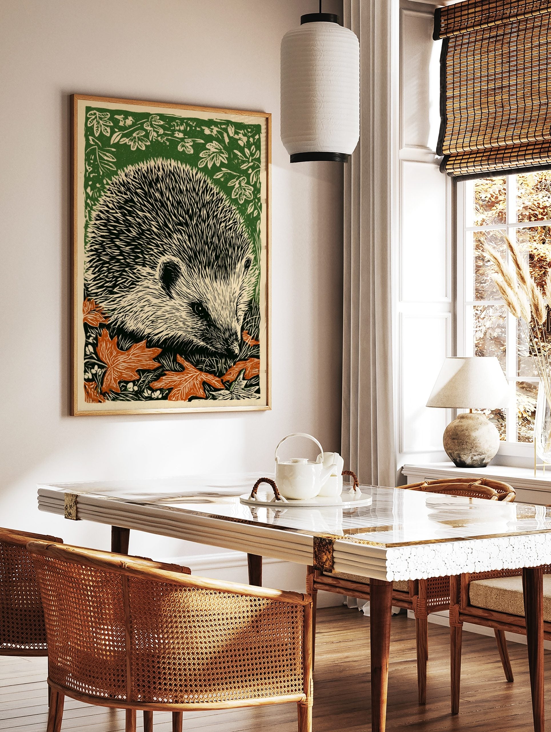 Linocut print of a hedgehog with black quills, off-white face, orange autumn leaves, and green, in a styled room mockup