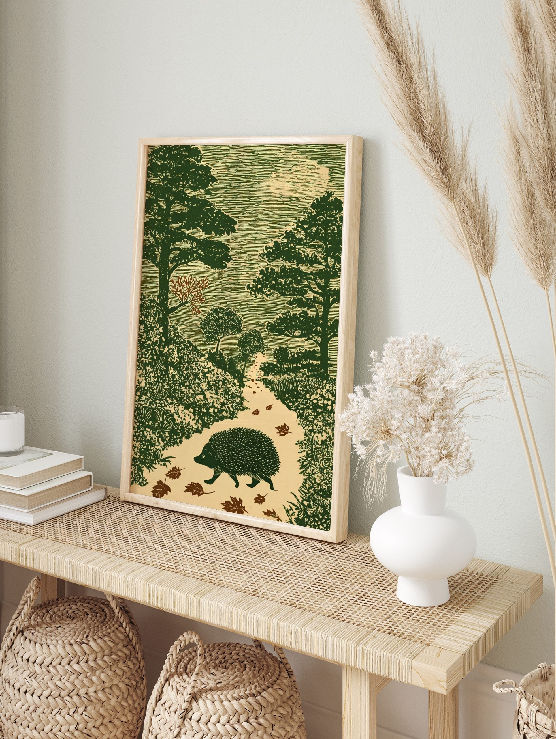 Hedgehog walking on an autumn forest path, surrounded by trees and leaves, in a green woodcut, in an alternate framed mockup