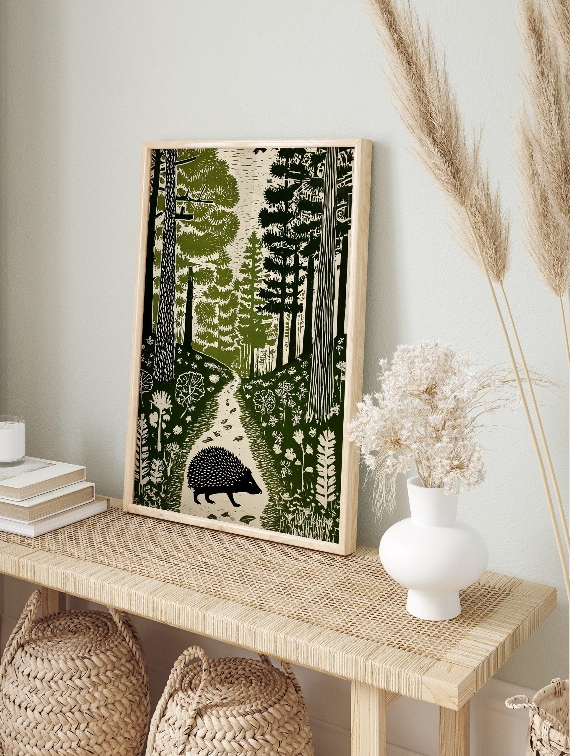 Hedgehog walking on a forest path, surrounded by trees and foliage in a green linocut style, in an alternate framed mockup