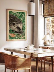 Hedgehog linocut print in green, black, and off-white, with orange leaves, in a portrait composition, in a styled room mockup