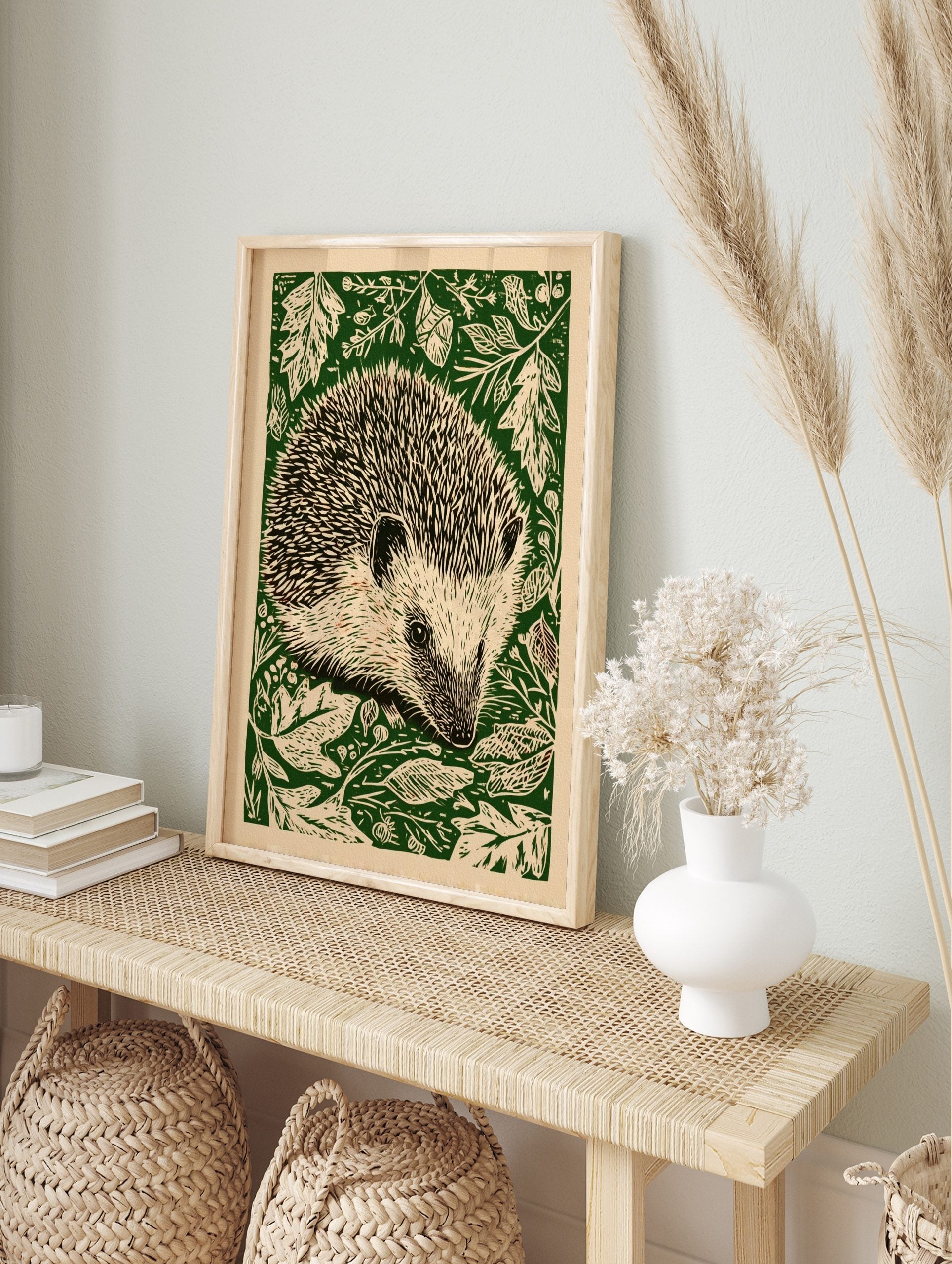 Hedgehog linocut style wall art print with green foliage on a cream background, portrait, in an alternate framed mockup