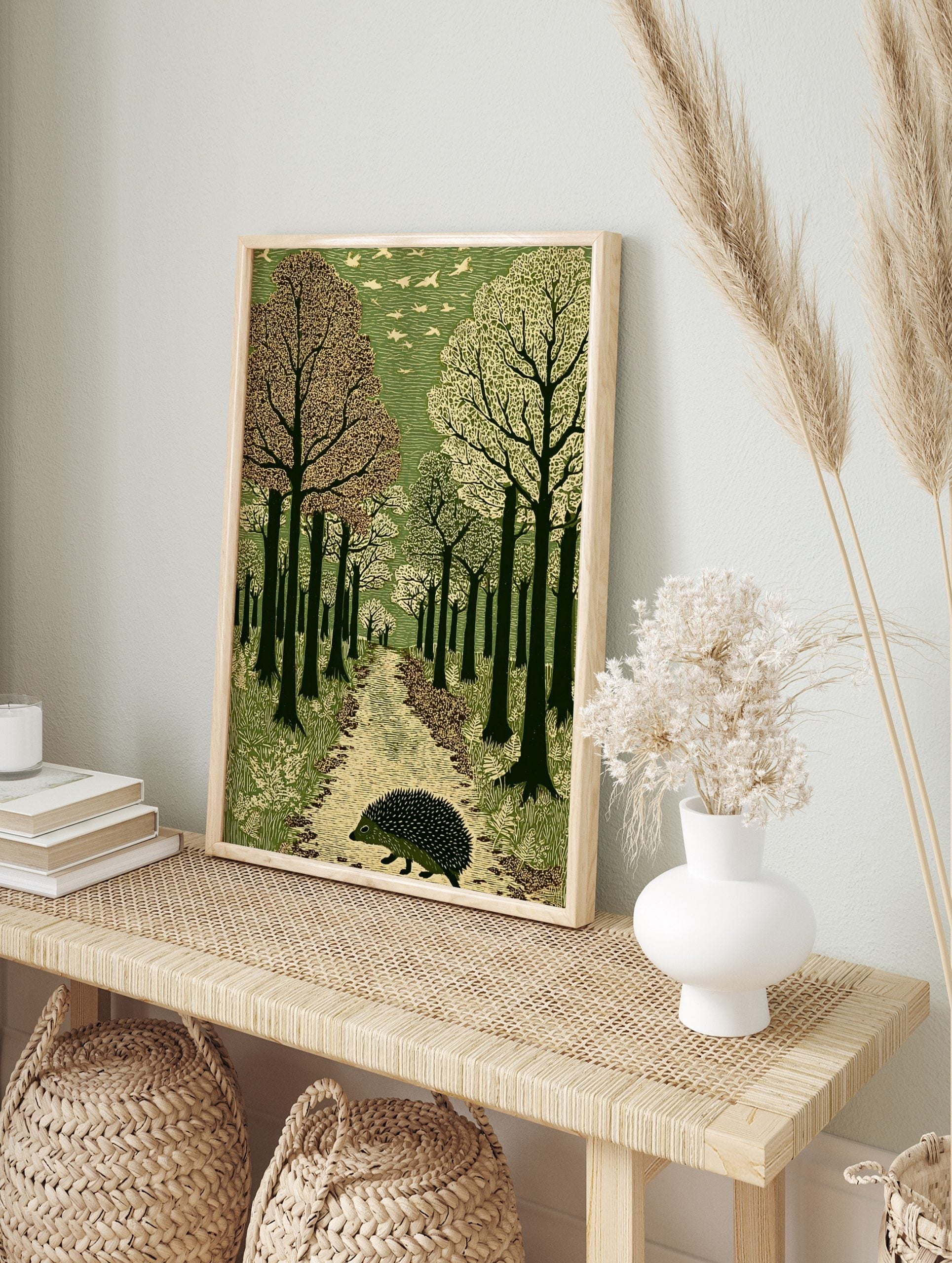 Hedgehog walking on a textured path through a green forest with flying birds, in a linocut, in an alternate framed mockup