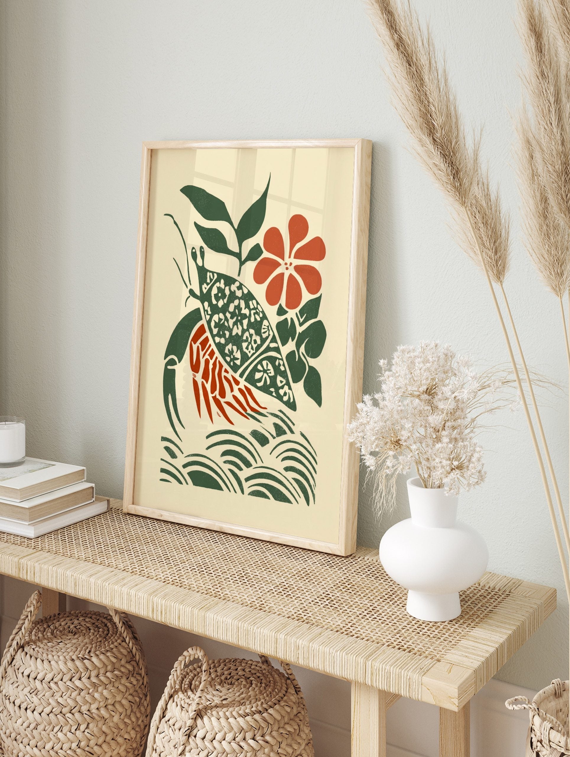Stylised hermit crab wall art with patterned green shell, red body, green leaves, red flower, in an alternate framed mockup