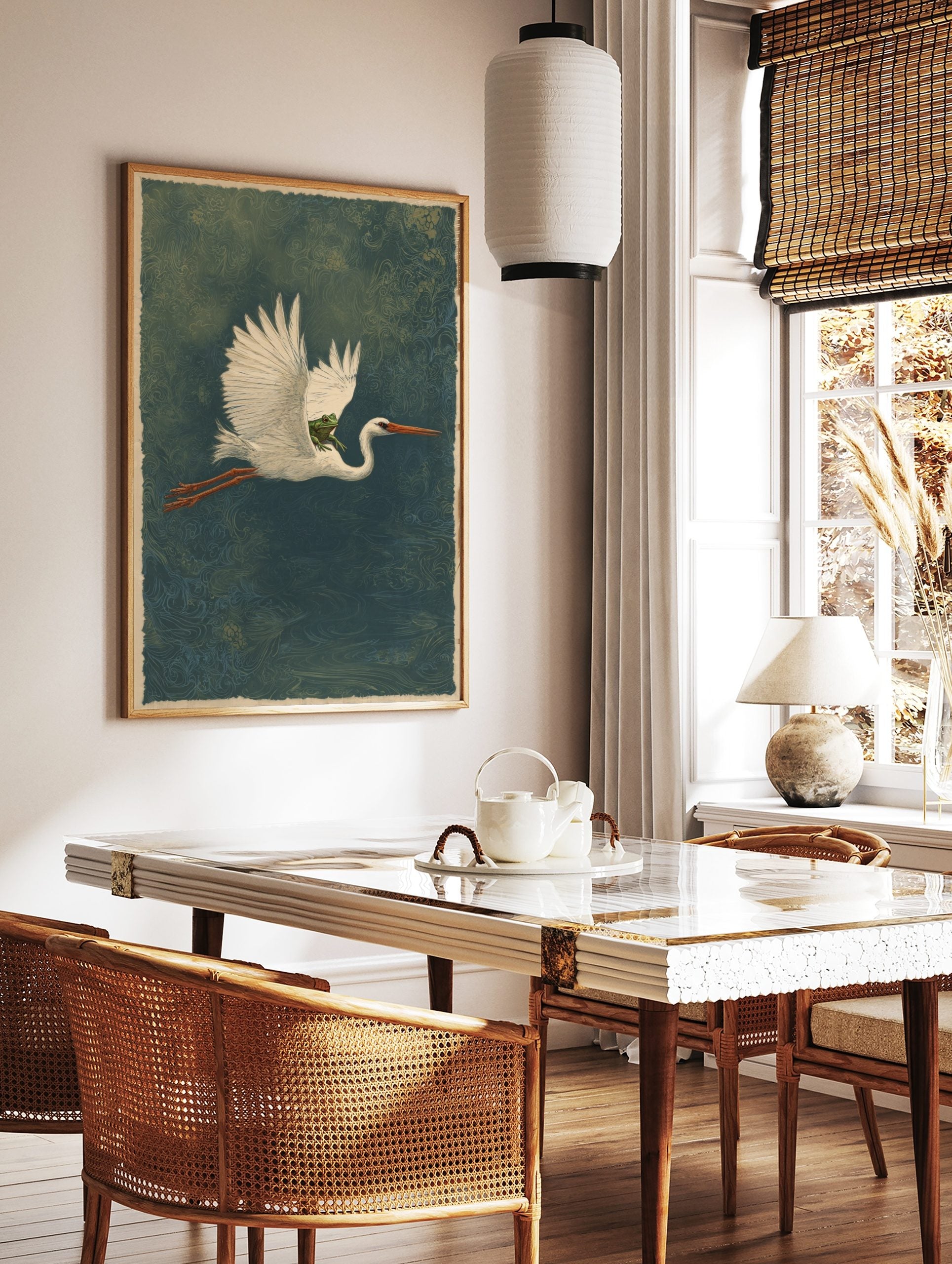 Illustrative white heron in flight carrying a green frog on its back, deep teal patterned background, in a styled room mockup