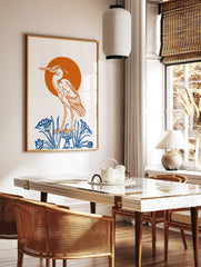 Illustrative heron bird standing on blue pedestal with blue plants, orange sun background, white, in a styled room mockup