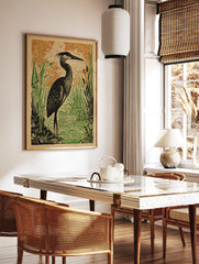 Illustrative print of a black heron bird in green wetland reeds and water, with an orange patterned, in a styled room mockup