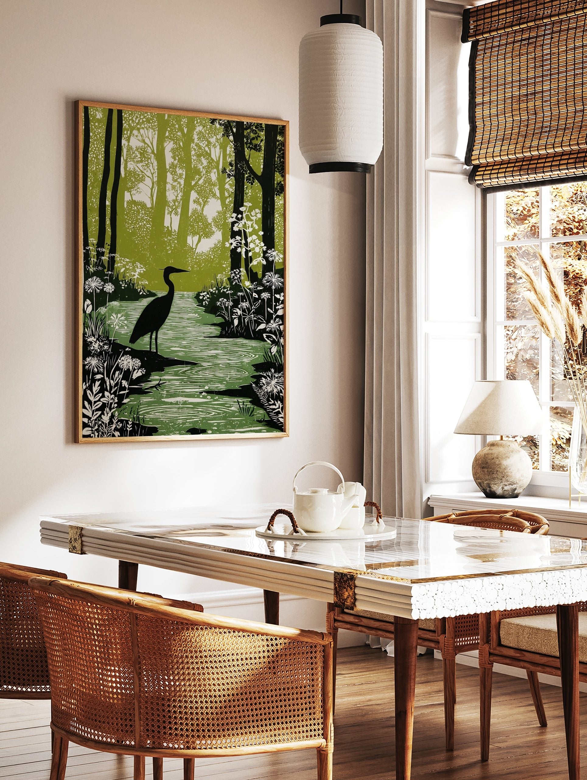 Linocut-style print of a black heron standing in a green forest stream with white flowers and tall, in a styled room mockup