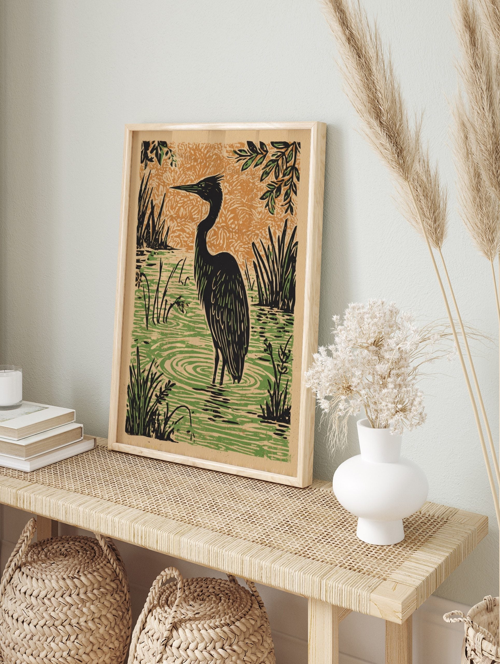 Black heron bird standing in green marsh water with reeds, against an orange textured sky in, in an alternate framed mockup
