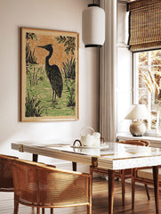 Black heron bird standing in green marsh water with reeds, against an orange textured sky in a, in a styled room mockup