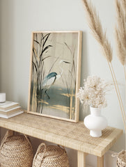 White heron bird standing among tall reeds with gold accents on a cream background, in an alternate framed mockup
