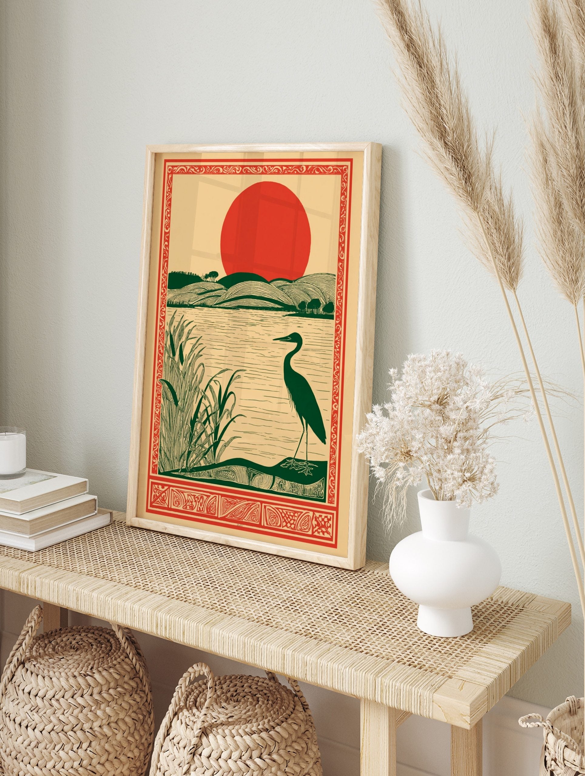 Illustrative art print of a dark green heron by a lake with reeds, rolling green hills, and a, in an alternate framed mockup